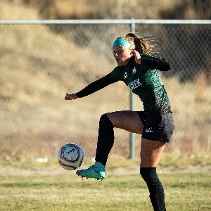 JV Girls Soccer player high kicks the ball